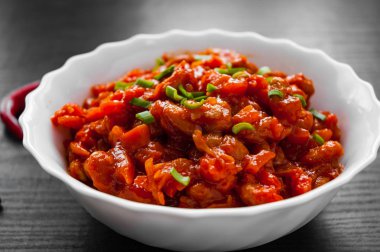 Koyu ahşap arka plan üzerinde kapta domates soslu sebze ve fasulye güveç