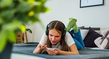Genç kız yatakta bir smartphone--dan evde müzik Mobil döşeme ile eğlenceli var