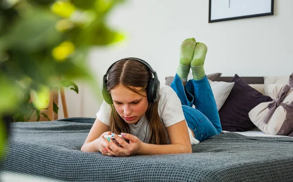 Genç kız yatakta bir smartphone--dan evde müzik Mobil döşeme ile eğlenceli var