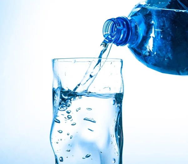 Close Menuangkan Air Dari Botol Gelas Latar Belakang Biru — Stok Foto