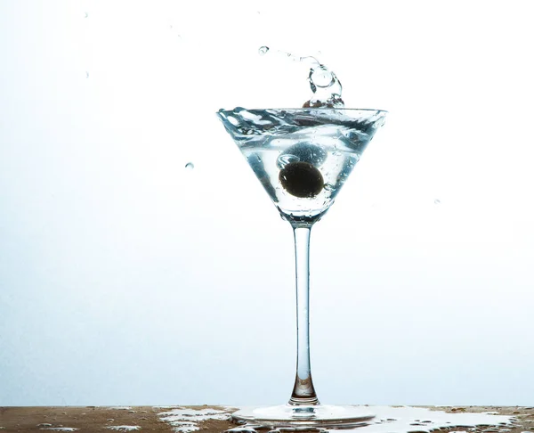 martini in glass with splashes and olives