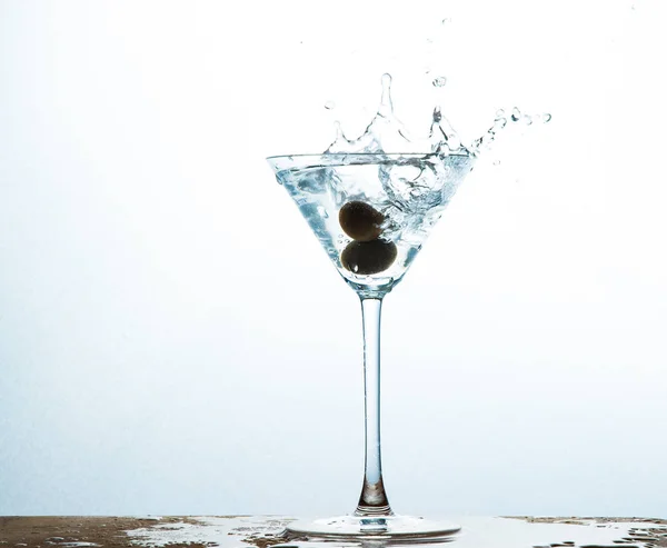 martini in glass with splashes and olives