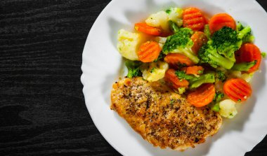 Karışık Sebzeli tavuk fileto. karnabahar, brokoli ve havuç ahşap arka plan üzerinde beyaz plaka.