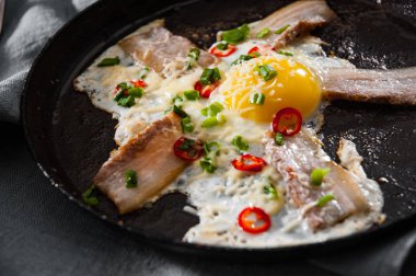 pastırma ve ahşap masa üzerinde bir tavada peynir ile kızarmış yumurta