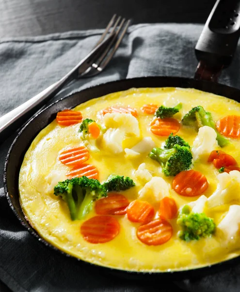 omelet with Mixed vegetables. cauliflower, broccoli and carrots in a frying pan on wooden table