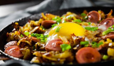 sosis ve patates ahşap masa üzerinde bir tavada kızarmış yumurta