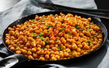 Ahşap masa üzerinde tavada kızarmış baharatlı nohut.