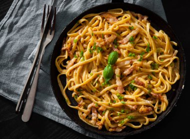 Geleneksel İtalyan makarna Carbonara koyu ahşap arka plan üzerinde bir tavada pişirme yakın çekim
