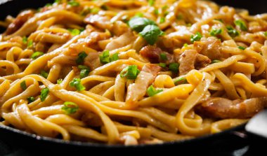 Geleneksel İtalyan makarna Carbonara koyu ahşap arka plan üzerinde bir tavada pişirme yakın çekim