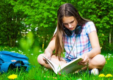 Öğrenci parkta. Neşeli mutlu genç kız öğrenci oturma ve üniversite kampüsü veya park dışında okuma.