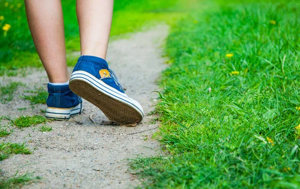 Caminhando Mulheres Perna Jeans Tênis Sapatos Estrada Grama Verde — Fotografia de Stock