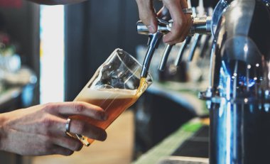 Bira musluğundaki barmen bir restoranda ya da barda servis edilen bardakta bira dolduruyor.