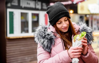Sokak yemeği. Yunan et jiroskopu tutan genç bir kadın. Tzatziki soslu, sebzeli, peynirli ve patates kızartmalı.