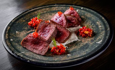  Ahşap masa arkasında orta pişmiş sulu biftek ve az pişmiş biftek.