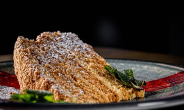 Tahta masadaki bir tabakta dilimlenmiş ballı kek.