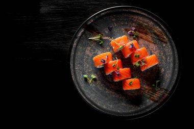 Somonlu suşi, avokado, siyah ahşap masa arkasında krem peynir.