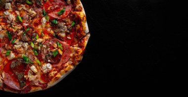 Mozzarella peynirli pizza, salam, tavuk eti, sığır eti, jambon, domates sosu, biber, baharat. Koyu gri arka planda İtalyan pizzası