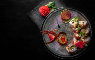 Siyah ahşap masa arkasında suşi yuvarlanıyor.