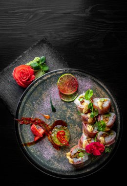 Siyah ahşap masa arkasında suşi yuvarlanıyor.