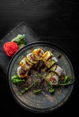 Siyah ahşap masa arkasında suşi yuvarlanıyor.