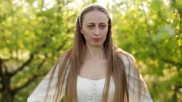 Une fille dans un jardin de printemps redressant ses cheveux et fermant les yeux . — Video