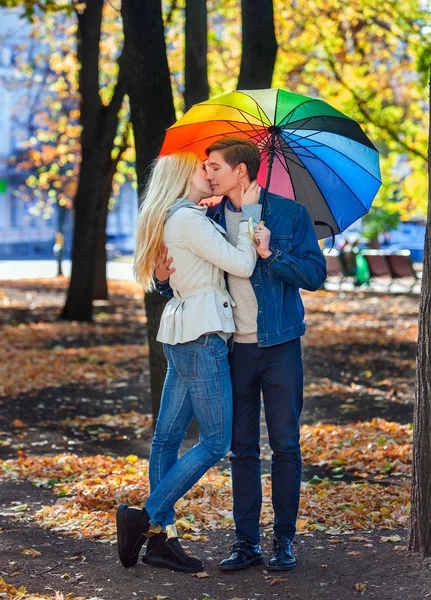 Pareja cariñosa en la fecha bajo paraguas besándose en el parque de otoño . — Foto de Stock