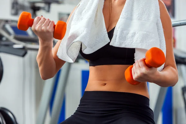 Mujer manos mantiene mancuernas en el gimnasio . — Foto de Stock