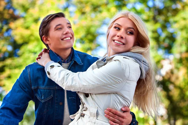 Ragazzo innamorato tiene ragazza le braccia nel parco autunnale . — Foto Stock