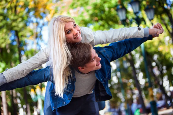 Ragazza innamorata abbraccia ragazzo per le spalle nel parco autunnale . — Foto Stock