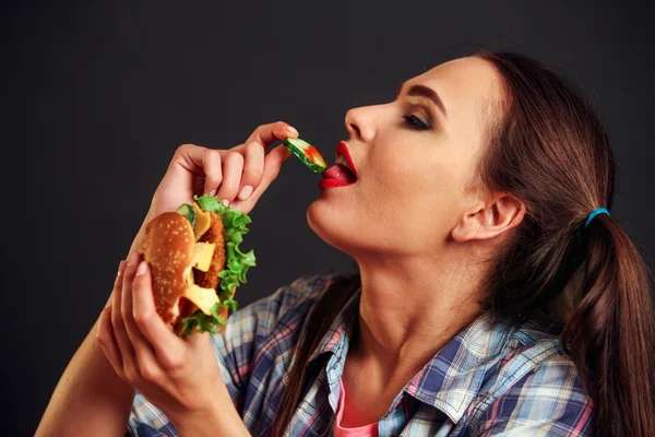 Dívka jíst hamburger s chuti k jídlu . — Stock fotografie