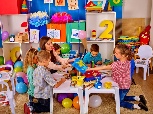 Niños con maestra pintando sobre papel en el jardín de infantes  . — Foto de Stock