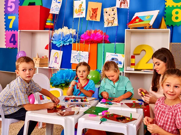 I bambini con insegnante stanno facendo qualcosa di carta colorata . — Foto Stock