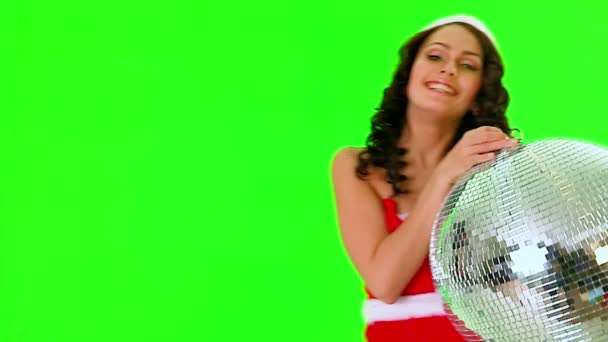 Frau im Weihnachtsmannkleid hält Discokugel. grüner Hintergrund. — Stockvideo