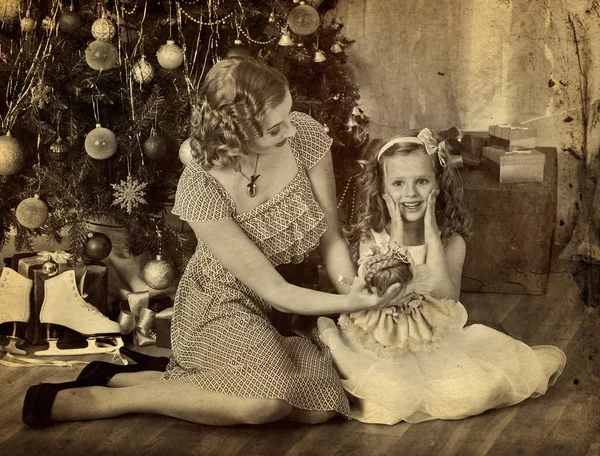 Barn med mor och docka nära julgran. — Stockfoto