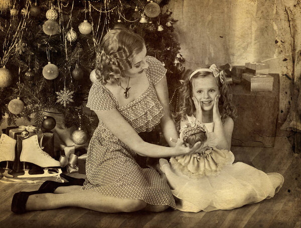 Child with mother and doll near Christmas tree.
