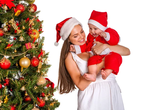 Mamá vistiendo sombrero de Santa sosteniendo bebé bajo árbol de Navidad . —  Fotos de Stock