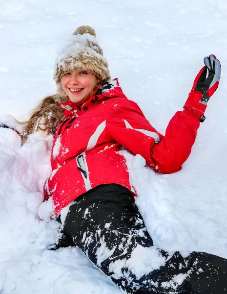 Adolescente menina vestindo roupas de inverno deitado na neve profunda  . — Fotografia de Stock