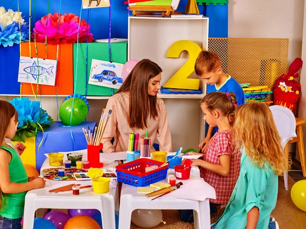 Niños con maestra pintando sobre papel en el jardín de infantes  . — Foto de Stock