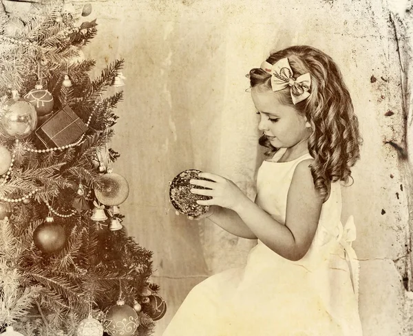 El niño decora el árbol de Navidad. Foto antigua sobre papel amarillo . —  Fotos de Stock