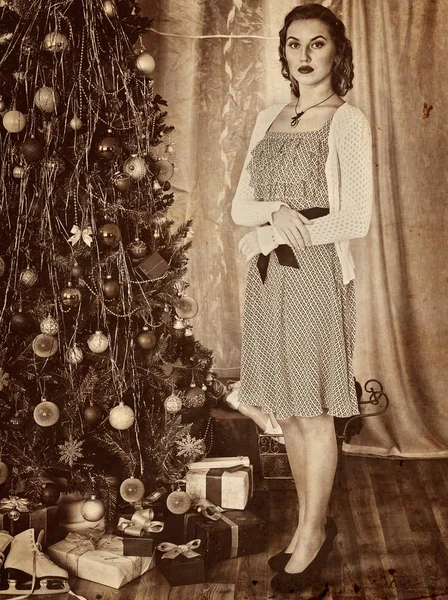 Woman receiving gifts under Christmas tree. Old photo yellow paper. — Stock Photo, Image