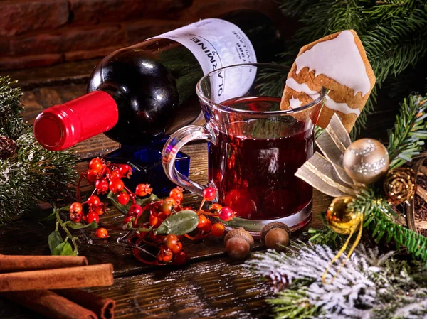 Wine bottle with mug lying on snow-covered fir branches.