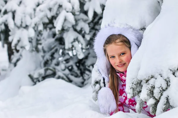 Portrait of little kid girl in winter clothes plying in deep snow. — Stock Photo, Image