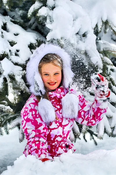 A criança, uma menina, brincando alegremente na neve . — Fotografia de Stock