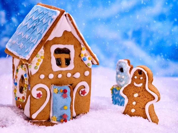 Natal homem de gengibre e casa na neve no fundo azul . — Fotografia de Stock