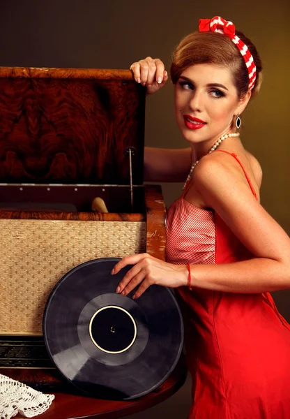 Retro woman with music vinyl record. Girl pin-up style wearing red dress.