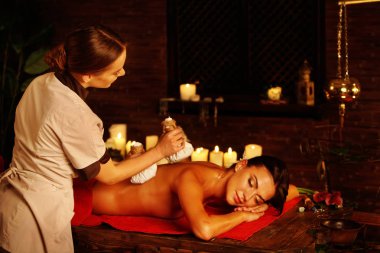 Masör masaj spa salonu içinde kadın. Otlar sıcak top terapi.