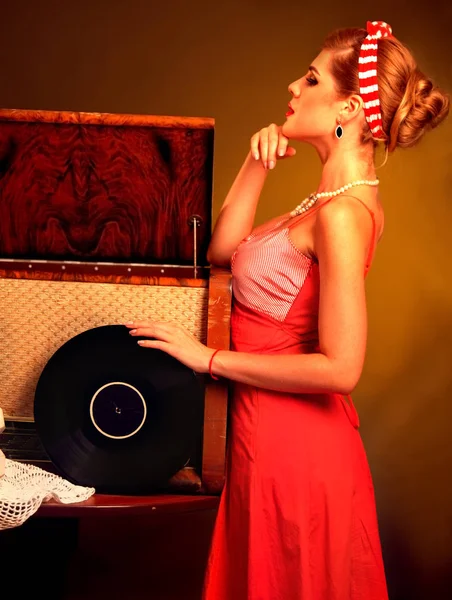 Mujer retro con disco de vinilo musical. Chica pin-up estilo usando vestido rojo . —  Fotos de Stock