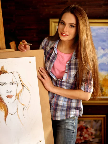 Pintura de artista sobre caballete en estudio. Chica pinta retrato de mujer con pincel . —  Fotos de Stock