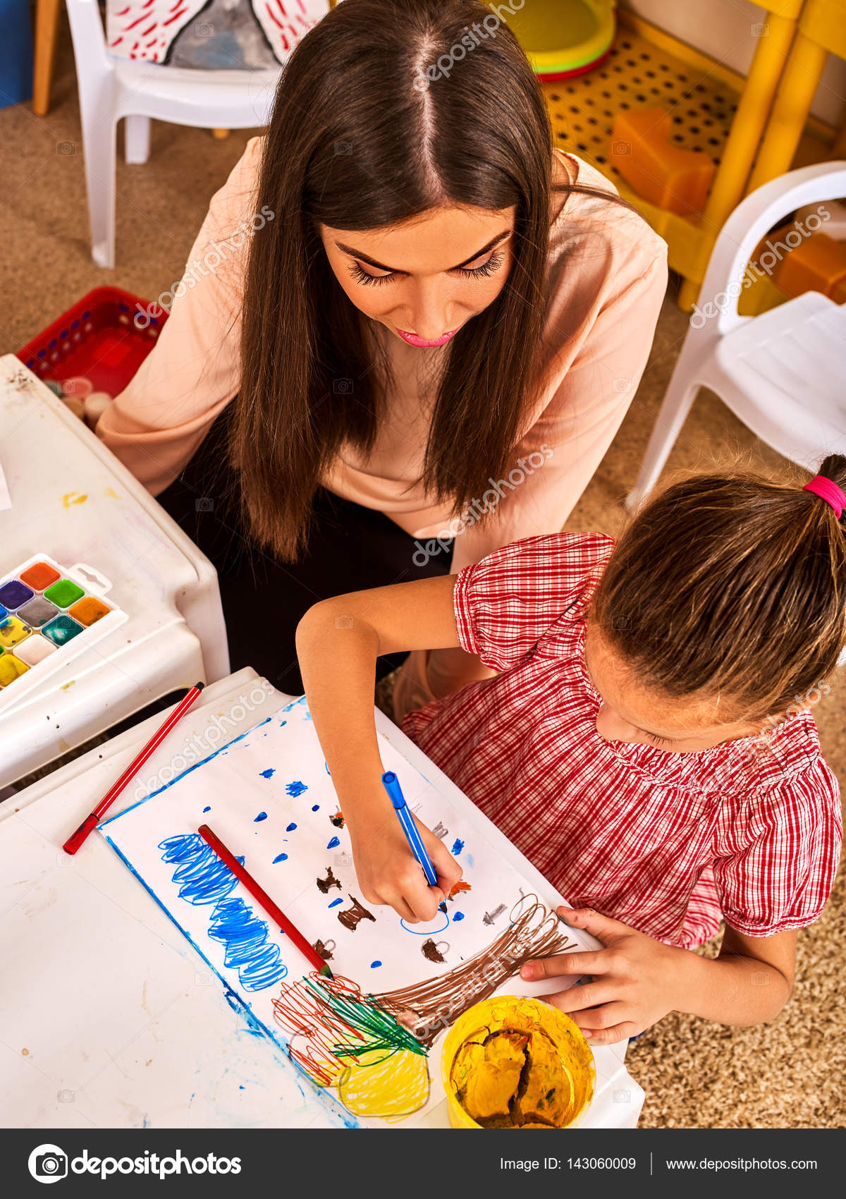 Scuola materna insegnante aiuto piccolo studente Ragazza del bambino colorare foto sul tavolo in classe Vista dall alto Amicizia con