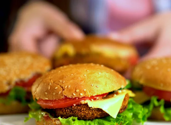 Fast-food hamburger met ham op een houten bord. Onscherpe achtergrond. — Stockfoto